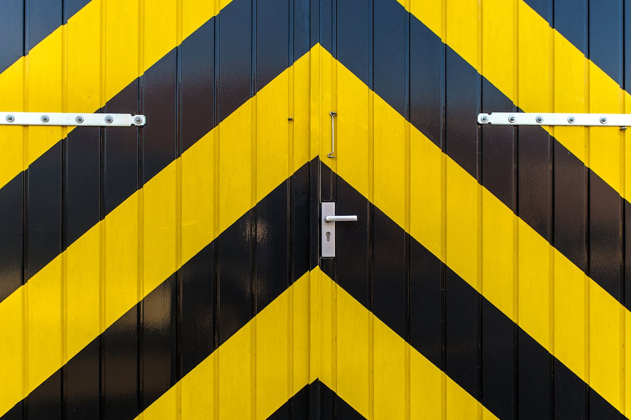 Close-up of a metal door with striking yellow and black diagonal stripes and a metallic handle.